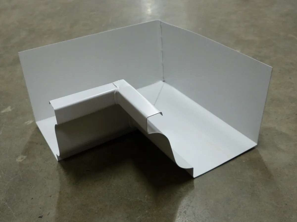 K-style aluminum gutter inner corner showing the characteristic ogee profile and flat back