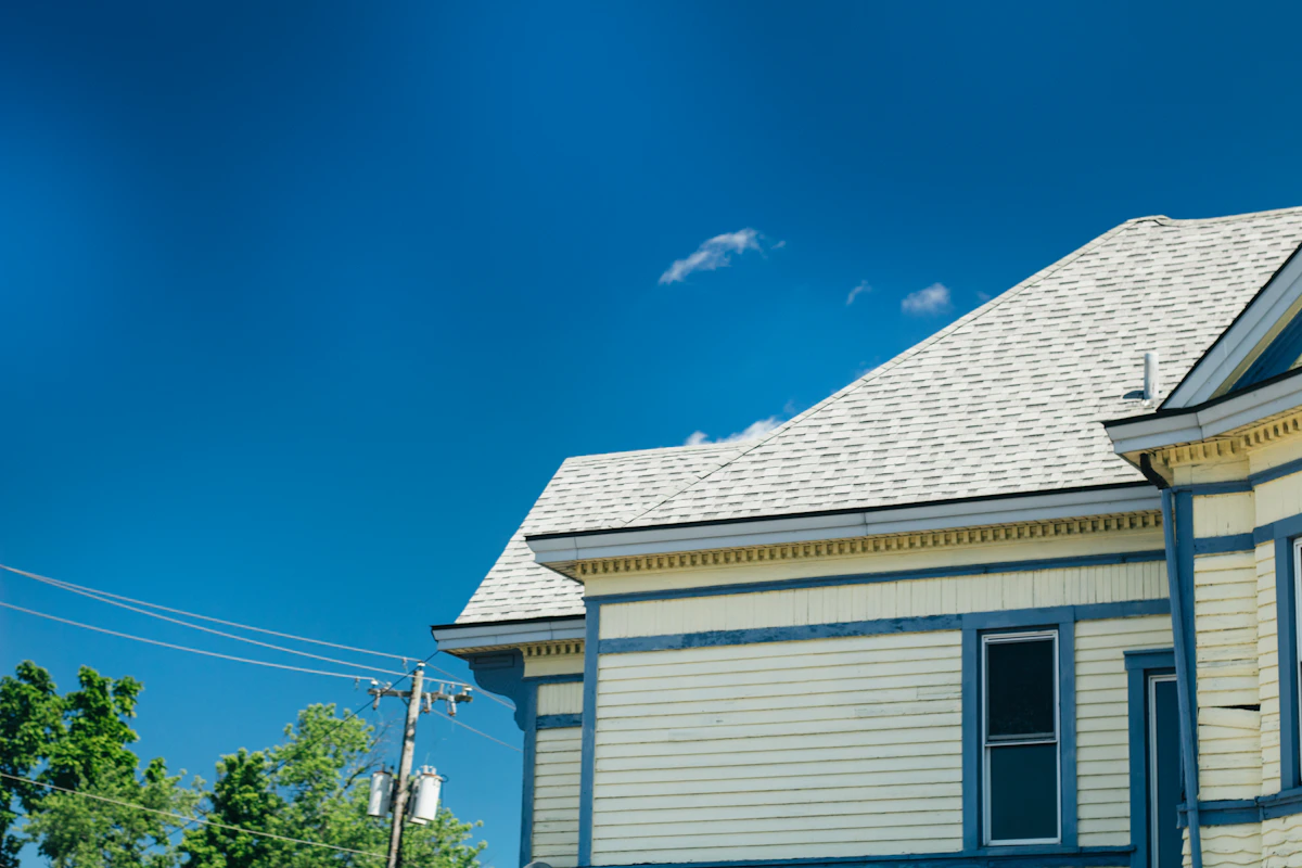 Clean white seamless gutters running along the roofline of a Charlotte NC home against a blue sky